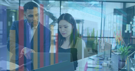 Examining two colleagues in suits pointing at laptop in open-plan office, with chart overlay