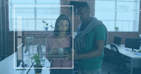 Collaborating software developers reviewing code and charts at open-plan office, with dual monitors