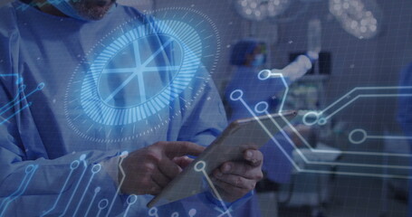 Tapping tablet, masked Hispanic surgeon viewing digital circuits in operating room, surgical lights