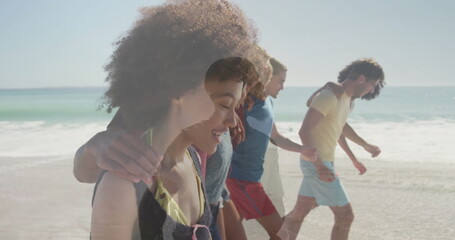Smiling woman merging with friends walking along sunlit beach, with swimsuit and waves, copy space