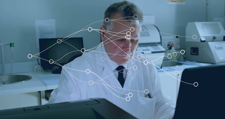 Analyzing technician wearing lab coat and tie focusing on computer screen in lab, with data overlay