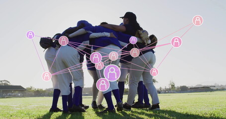 Huddling before game seven softball players holding gloves linking arms on field, with pink network