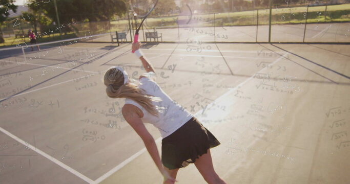 Serving tennis player wearing tennis skirt swinging racket on park court, with chain-link fence - Powered by Adobe