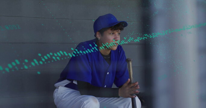 Sitting teen in blue uniform and cap gripping wooden bat on dugout bench, gazing toward field - Powered by Adobe