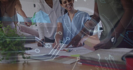 Leaning women pointing, discussing design sketches in office meeting, with digital overlay