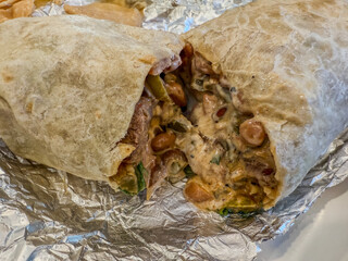 A steak burrito broken in half with cheese oozing