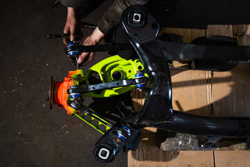 Fototapeta premium Custom rear suspension setup in progress for drift car project. Rear Suspension and Hub Assembly Installation. Building drift car rear suspension with fresh bushings, vibrant arms, and restored hub.