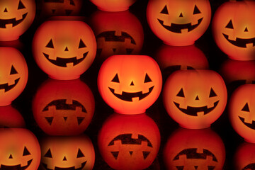 Numerous pumpkins with carved faces in a photo