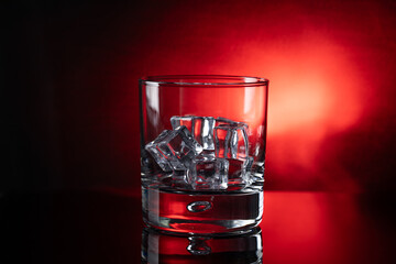 Glass with ice against red background