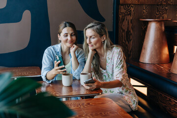 Two modern pretty women use mobile phones for social networking.