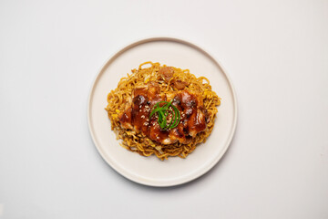 Close up top view of delicious fried noodles served with grilled chicken on white ceramic plate, Asian cuisine concept on white background.
