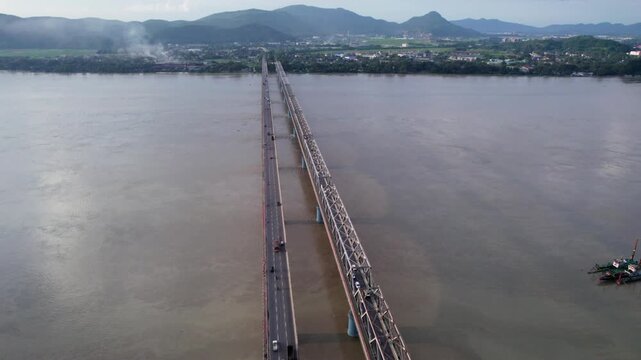 New Saraighat Bridge spanning the Brahmaputra River with a city and mountains in the background