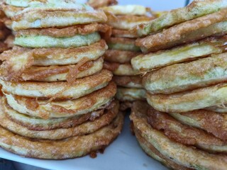 A stack of fried food, including fried potatoes and fried onions. The stack is piled high and he is very tasty