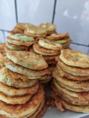 A stack of fried zucchini slices. The zucchini slices are stacked on top of each other and are golden brown in color