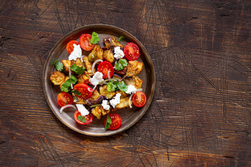  Georgian salad with deep fried eggplant, tomatoes, onions, feta cheese and cilantro copy space for text. Vegetarian food with eggplant and other vegetables, top view