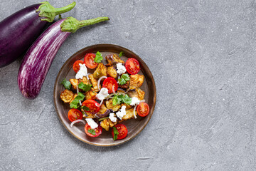  Georgian salad with deep fried eggplant, tomatoes, onions, feta cheese and cilantro on the grey...