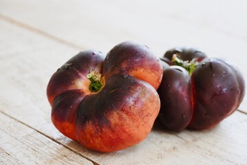 Black tomatoes displayed on a rustic wooden table.