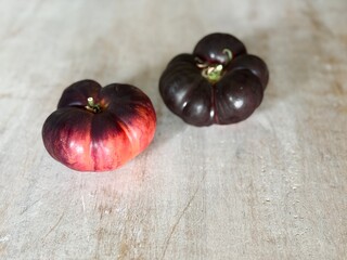 Black tomatoes displayed on a rustic wooden table.