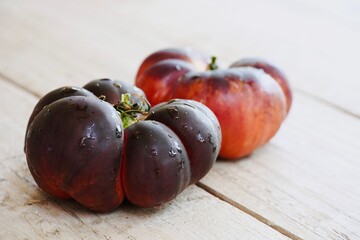 Black tomatoes displayed on a rustic wooden table.