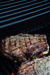 Well grilled huge steak on BBQ gas grill searing hot with grill marks crossed, and lots of seasoning.