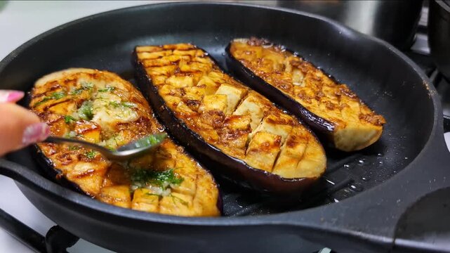 Sprinking aromatic herb mix onto charred eggplant slices sizzling in cast-iron grill pan