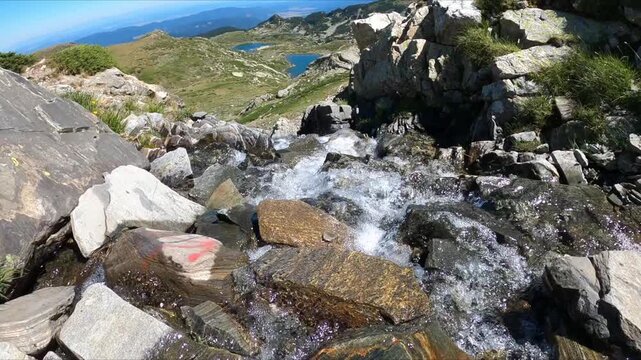 Slow motion of the Clear mountain stream flows over rocks on a sunny summer day. River and landscape idea. Nature and travel concept.