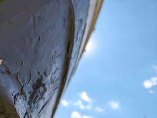 A wall with a blue sky in the background. The wall is covered in dirt and has a few cracks