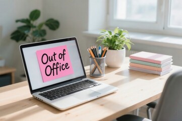 Laptop with out of office note on desk in bright workspace with plant, pencils, and notebooks representing break and rest time in work.