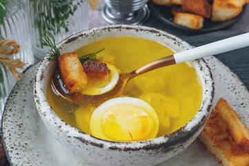 chicken broth with egg. Chicken soup with pieces of boiled fillet and halves of a quail egg. The soup is served with croutons