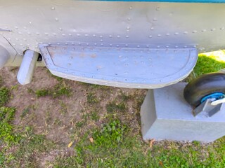 A grey airplane with a grey step on the side. The step is on the side of the plane and is made of metal