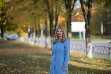 Portrait of a beautiful young blonde girl in a city park.