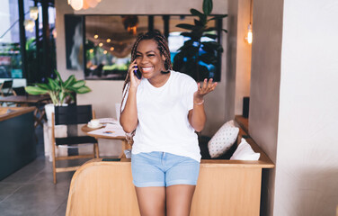 Joyful Black woman gestures while talking on smartphone, expressing energy, clarity, and communication power in dynamic tech-based freelance life.