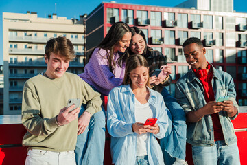 A lively group of diverse teenagers enthusiastically engaging with their mobile devices, sharing moments and applications, creating a sense of connectivity and friendship among them in a fun