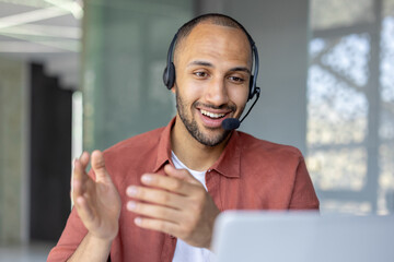 A cheerful man engaged in a virtual meeting, wearing a headset and talking enthusiastically.