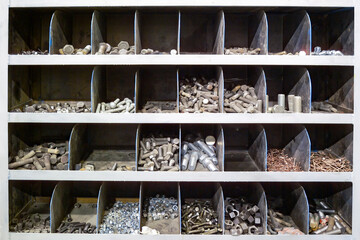 A close-up of an industrial storage rack, with various bolts, nuts, and screws neatly organized in different compartments.