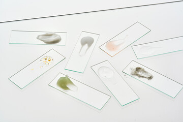Fototapeta premium Textures of various cosmetic products on slides on a gray background.