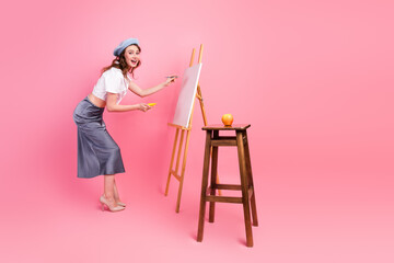Charming Young Woman Creates Art on a Pink Background With an Apple and Canvas Demonstrating Style and Creativity