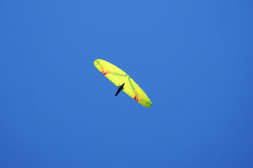 Flight yellow paraglider in blue sky parachute-wing
