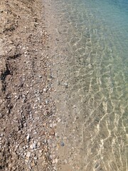 Seeufer mit Kiesel und klarem, frischem Wasser von oben, Teich im Urlaub