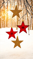 Four star-shaped Christmas ornaments, two red and two textured gold, hang from frosted branches over a snowy ground . Concept of Christmas decorations, holiday season, festive, winter, celebration.