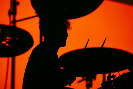 Drummer silhouette against orange stage background

