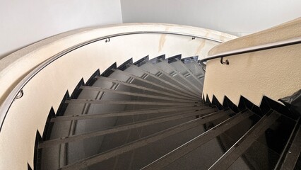 Fototapeta premium Modern Spiral Staircase with Black Granite Steps and Cream Walls.