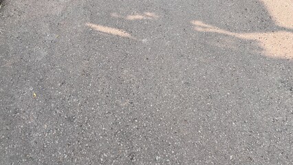 Textured Grey Asphalt Road Surface with Sunlight and Shadows.