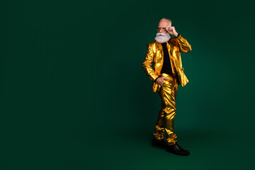 Elegant elderly gentleman in a golden suit celebrating a festive occasion against a green backdrop