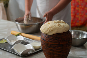 A male cook prepares dough for pies, his hands are stained with wheat flour