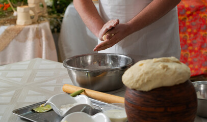 A male cook prepares dough for pies, his hands are stained with wheat flour