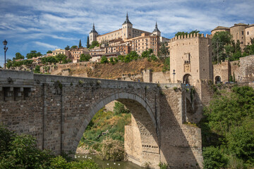 Sunny View of the Puente de Alc&aacute;ntara and the Alc&aacute;zar of Toledo in Spain. Unesco Stone Fortification on Hill. Cultural Heritage in Europe.