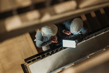 Architects using tablet on construction site stairs