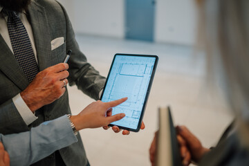 Architects using digital tablet showing blueprint to discuss construction project