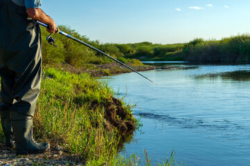 An elderly man fishing with a fishing rod on the river